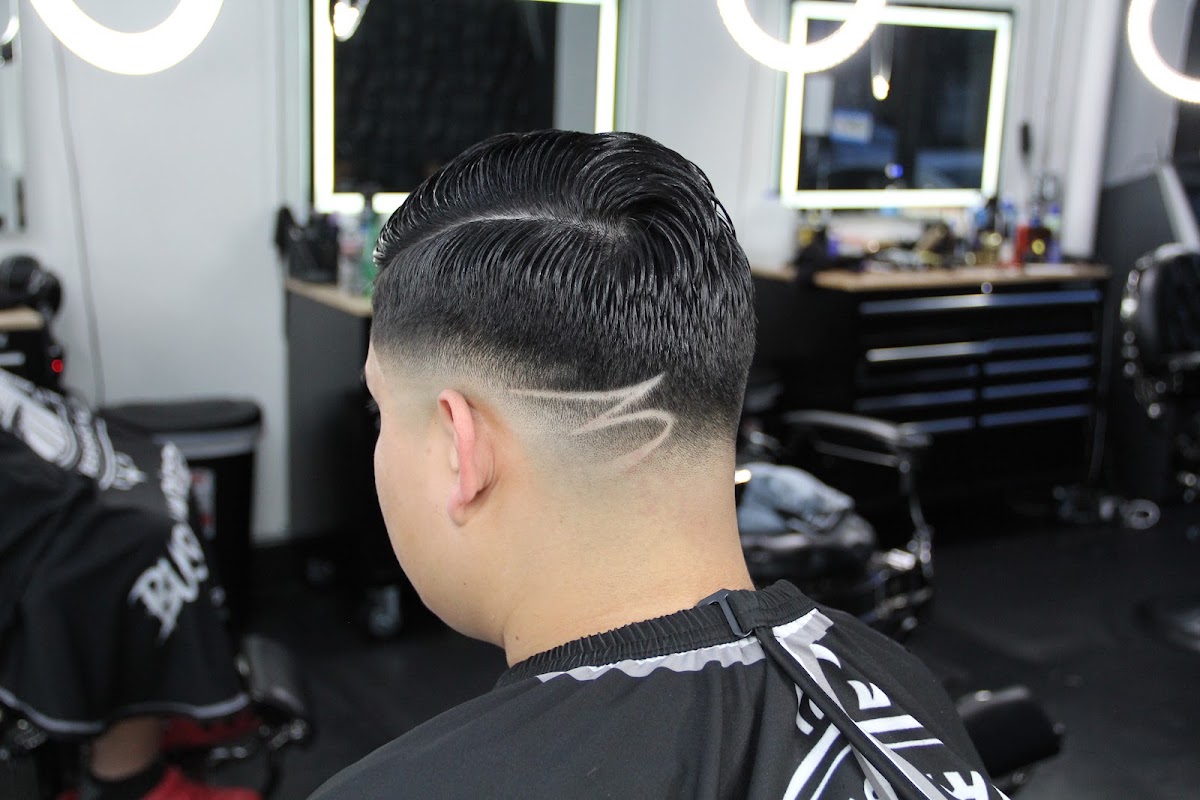 A taper fade with a freehand design line carved in and a comb over on top